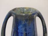 a blue vase with a handle on a white table