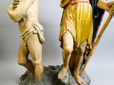 une statue représentant un homme et une femme tenant un bâton