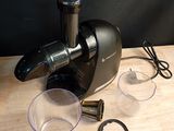 un extracteur de jus noir posé sur une table en bois