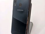 a close up of a cell phone on a stand on a white surface