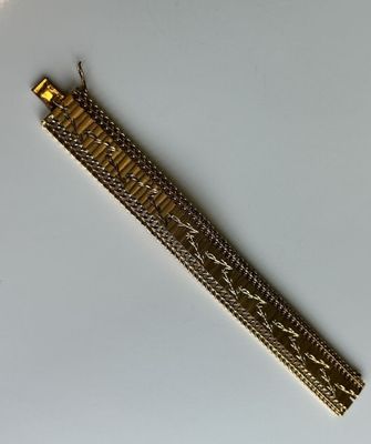 un gros plan d'un bracelet doré posé sur une surface blanche