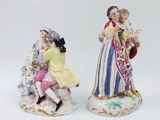 two figurines of people sitting on top of a white surface