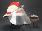 a hat with a face shield on it next to a suitcase