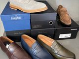 several pairs of men ' s shoes sitting on top of boxes on a table