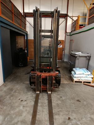 un chariot élévateur dans un entrepôt, avec des palettes au premier plan