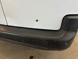 the rear bumper of a white van with a hole in the bumper