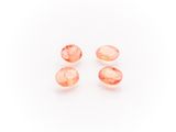 a group of three peach quartz beads on a white background