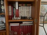 une bibliothèque sur laquelle sont posés de nombreux livres et verres