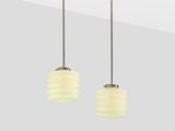 a pair of white glass pendant lights hanging from a ceiling