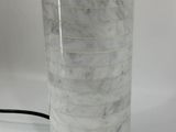 a white marble table lamp with a black cord on it