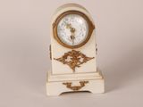 a small white and gold clock sitting on a table