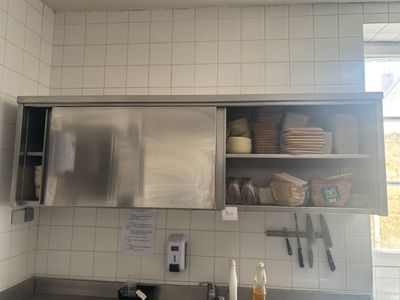 une cuisine équipée d'un plan de travail en inox et d'une armoire en inox