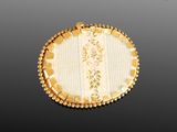 a close up of a gold and white broochle on a black background