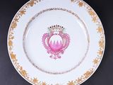 une assiette rose et dorée ornée d'une couronne