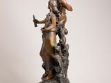 bronze statue of a woman holding a bird on a pedestal