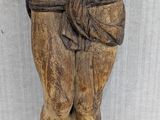 an old wooden statue of a man with a tie around his waist