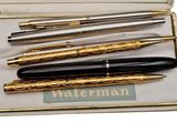 three fountain pens in a box with gold trims and a black one