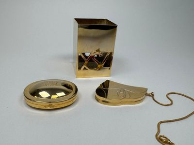 une montre de poche en or et un collier en or posés sur une surface blanche