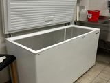 un congélateur coffre blanc posé dans une cuisine à côté d'un tabouret