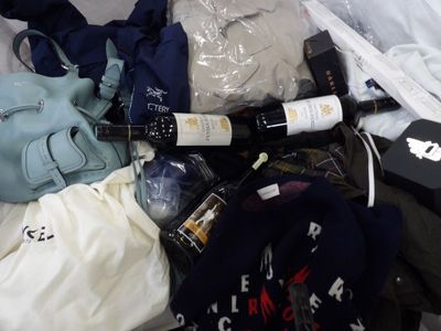 a bag of clothing and a bottle of wine on a bed