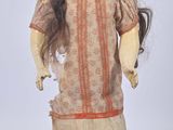 an old doll with long hair wearing a dress and a red flower in her hair