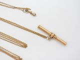 three gold necklaces and a necklace with a chain on a white surface