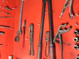 many tools hanging on a red wall in a garage