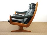 a black leather chair with a wooden frame on a carpeted floor