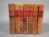 six vieux livres sont alignés sur une surface grise