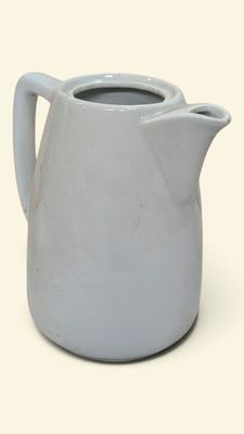 a white pitcher with a handle sitting on a table