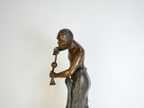 statue en bronze représentant un homme jouant de la trompette, posée sur un socle en marbre