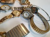 many watches and bracelets laid out on a table