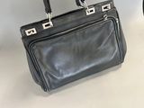 black leather handbag with silver hardware on top of a white table