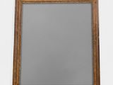 un miroir ancien en bois avec un cadre doré accroché à un mur blanc
