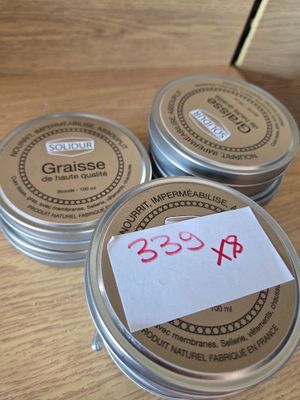 three tins of wax sitting on top of a wooden table