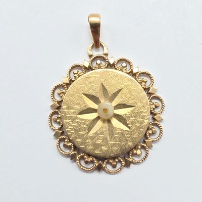 une image représentant un pendentif en or avec une étoile au centre