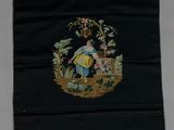 un vieux sac noir brodé, sur lequel sont représentées une femme et des fleurs