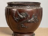 a brown vase with a bird on it sitting on a table