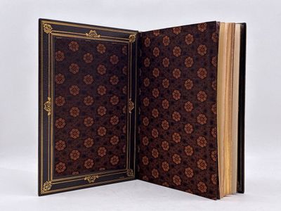 un livre ouvert orné d'un motif floral, posé sur une surface blanche