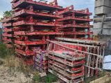 un grand tas de palettes rouges empilées au milieu d'un champ de terre battue