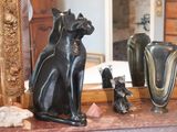 a statue of a cat sitting on top of a table next to a mirror