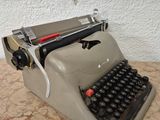 une vieille machine à écrire posée sur une table près d'un mur