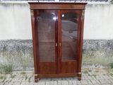 une armoire en bois avec des portes vitrées, placée contre le mur d'un immeuble