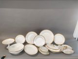 a lot of white and gold plates and bowls on a shelf