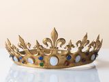 gold crown with blue and green stones on a white surface