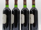 four bottles of wine are lined up in a row on a white surface