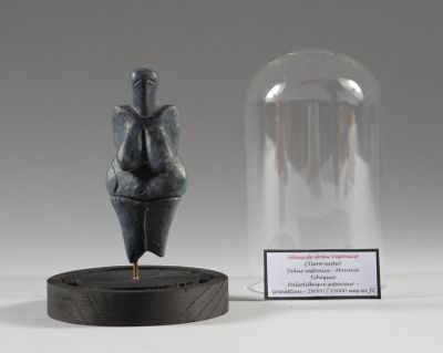 une petite statue représentant une personne, placée sous un dôme en verre
