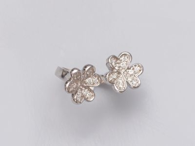 une paire de boucles d'oreilles en forme de fleur en diamant sur fond blanc