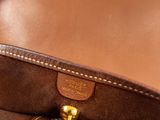 brown leather bag with gold hardware on white surface with white background