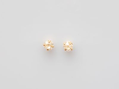 a pair of small gold stud earrings on a white background